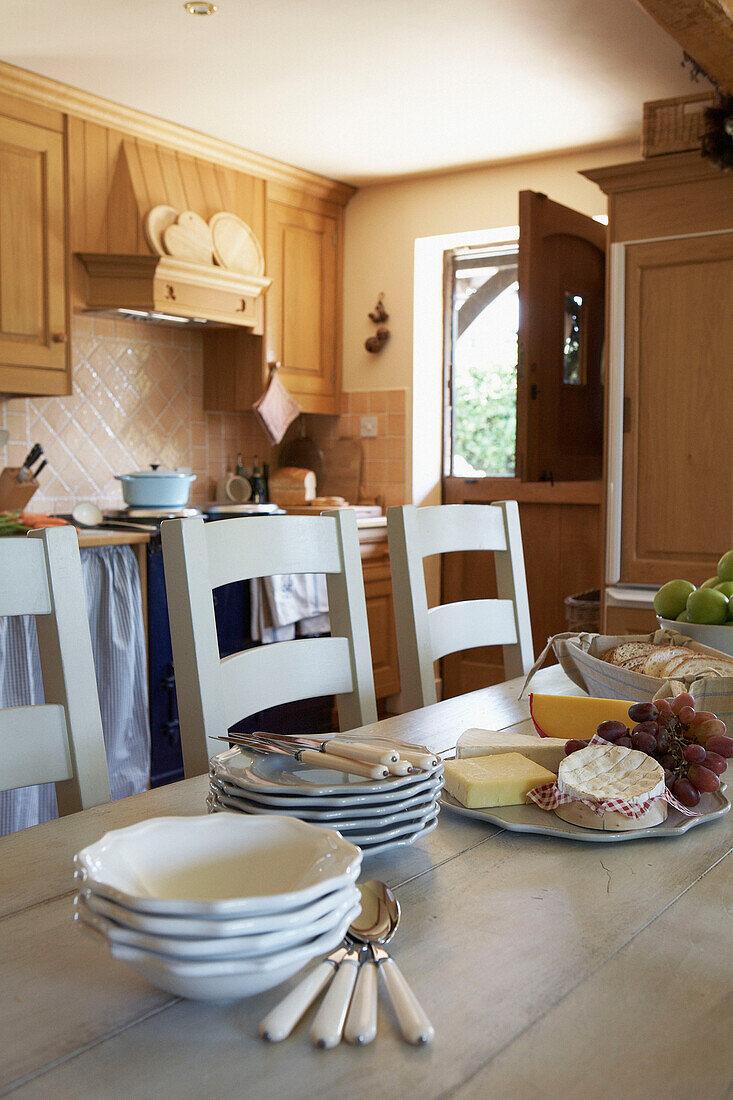 Cheeseboard with plates and cutlery on kitchen table