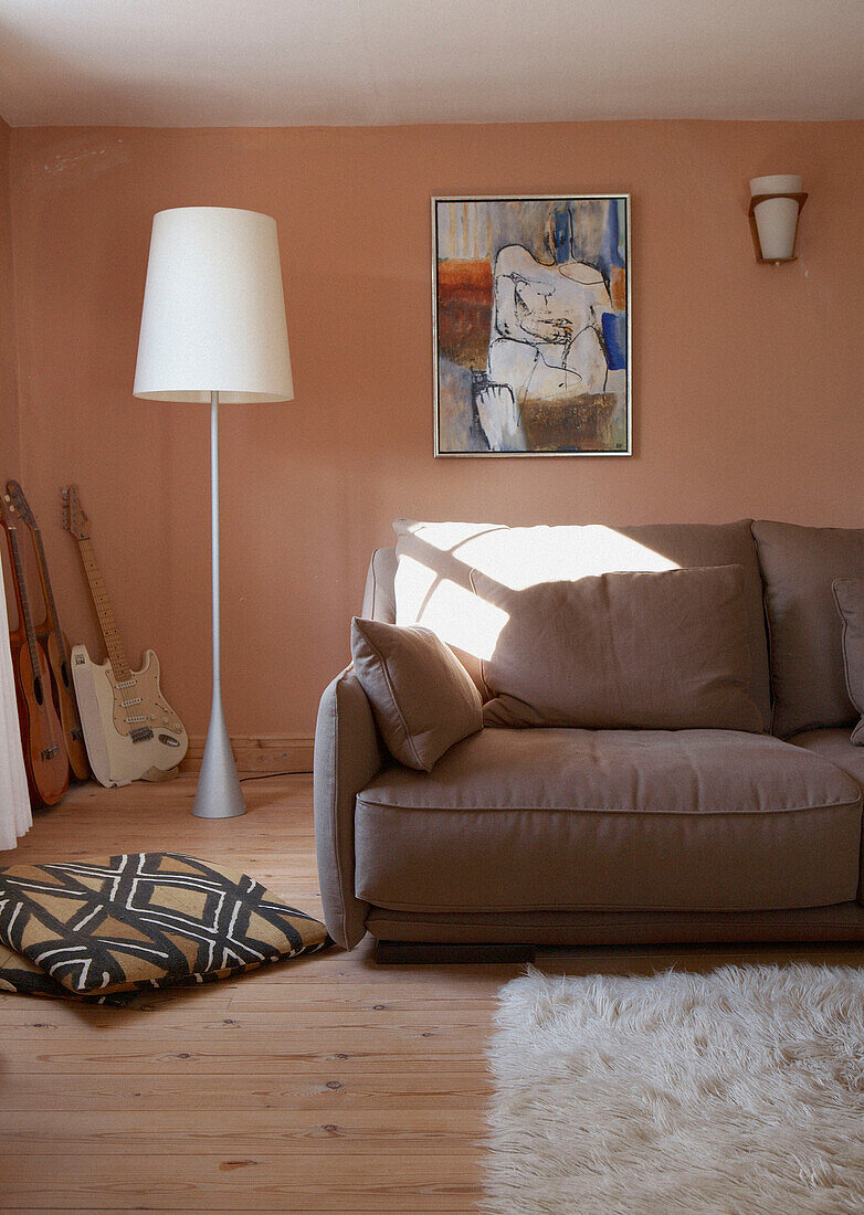 Light brown sofa in peach living room with oversized floorlamp 