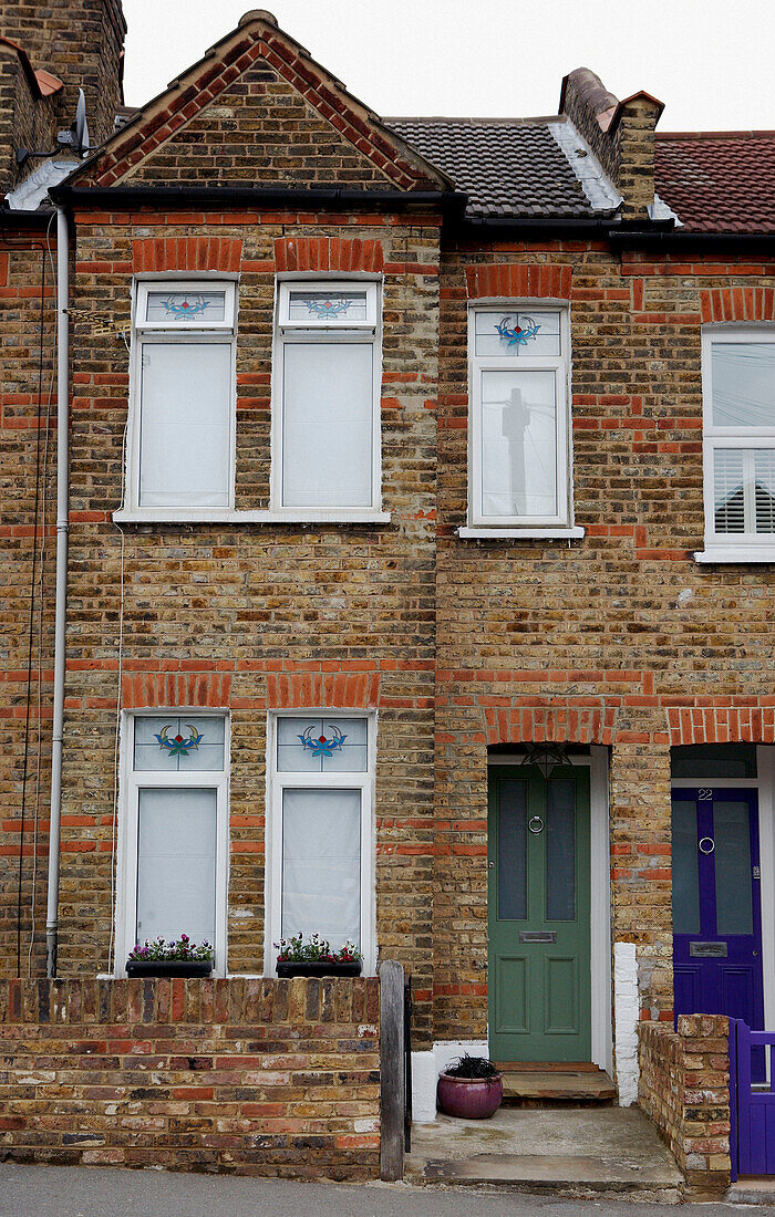 Brick home exterior with stained glass upper windows and window boxes