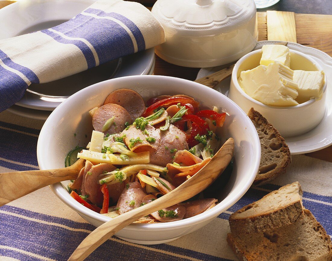 Swiss sausage salad in bowl, decoration: bread, butter etc