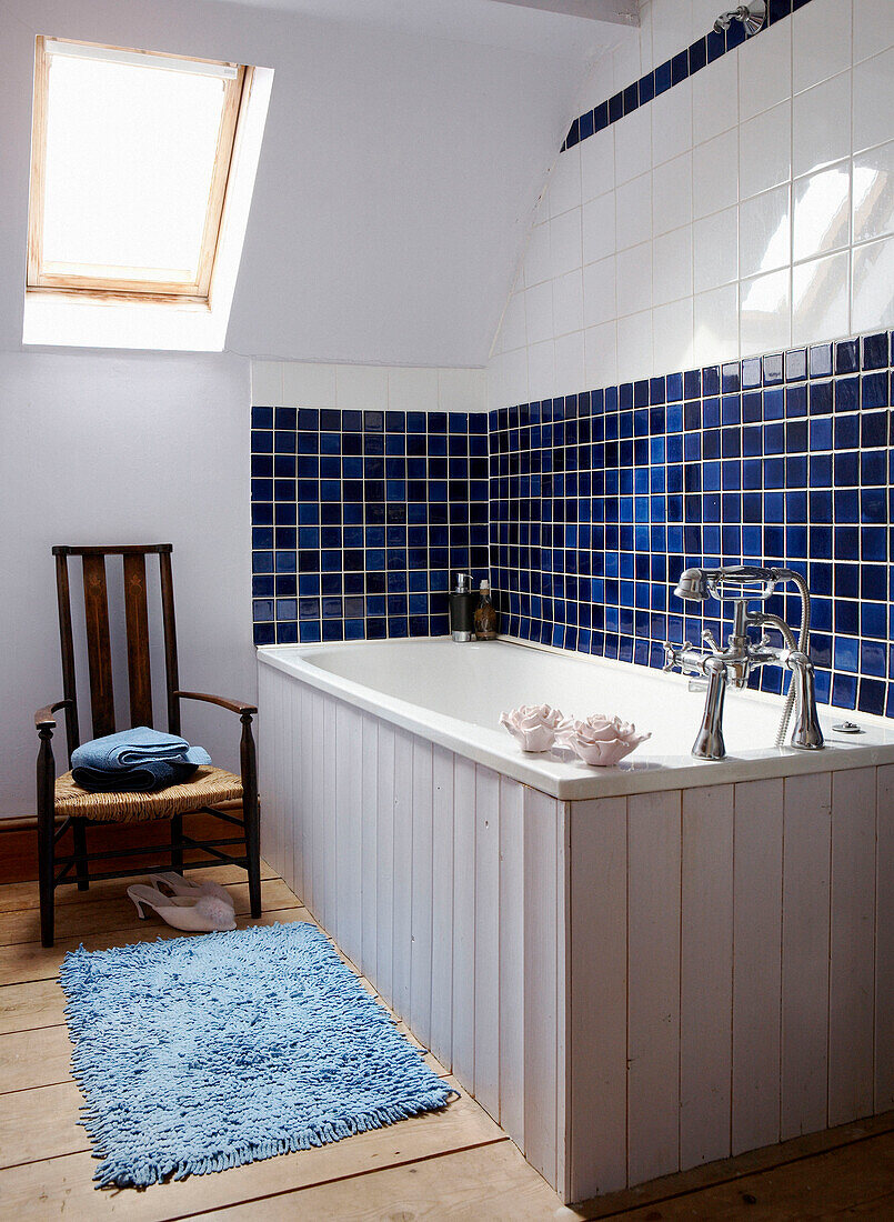 Panelled bathtub in blue tiled Georgian townhouse bathroom with skylight