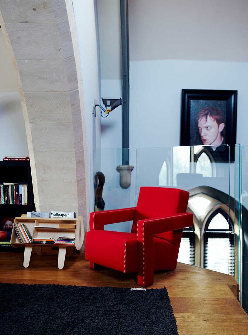 Red armchair with magazine rack in mezzanine conversion of Richmond school church 