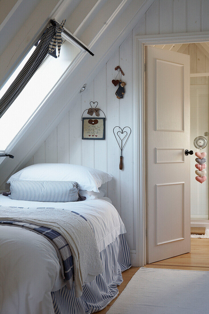 Attic bedroom with wall ornaments on tongue and groove panelling