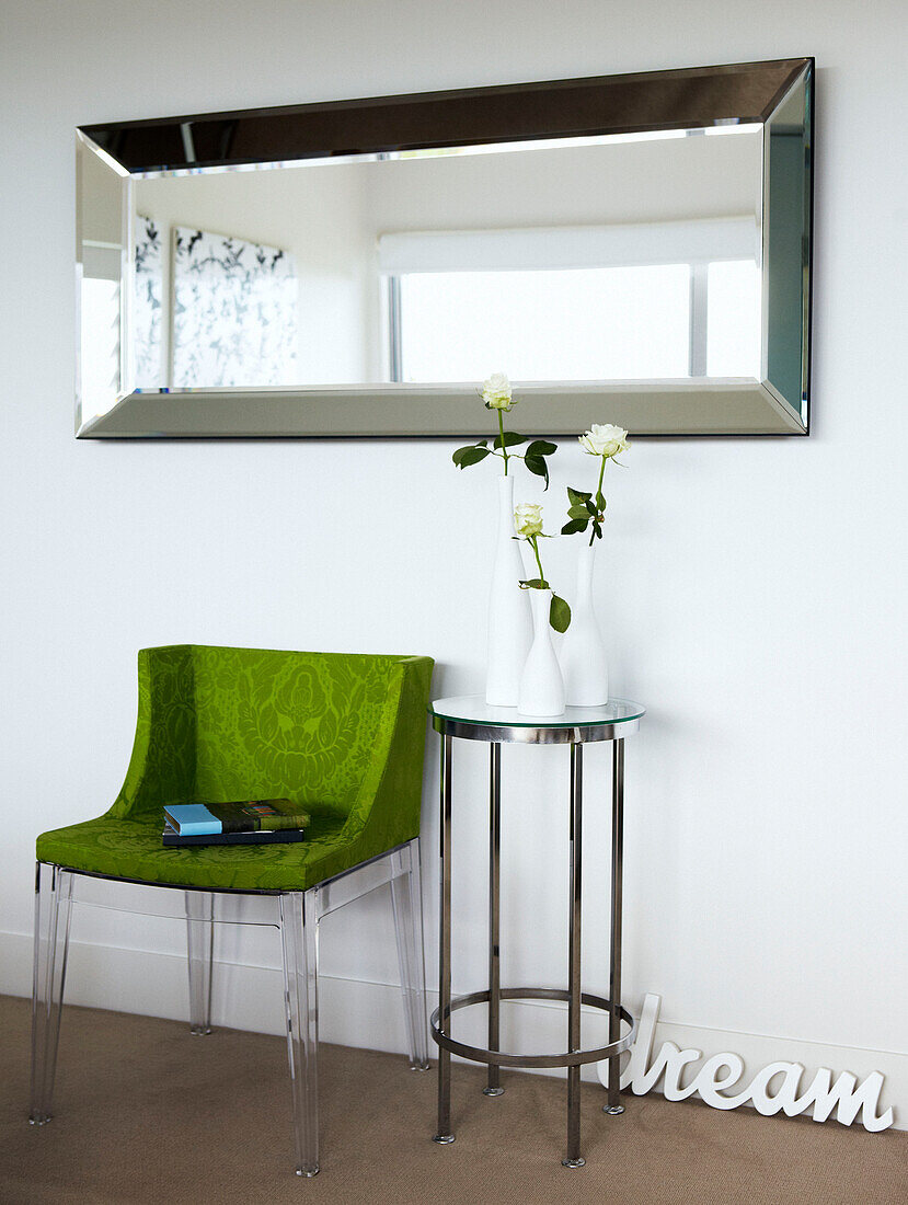 Lindgrüner Stuhl und metallgerahmter Beistelltisch unter dem Spiegel