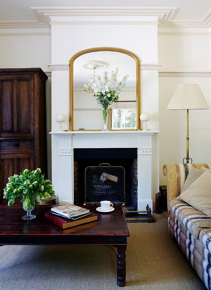 Gilt framed mirror on fireplace with wooden coffee table in townhouse living room