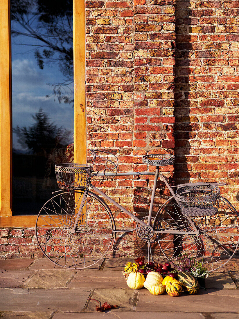 Altmodisches Fahrrad und Gemüse an der Backsteinfassade eines Landhauses