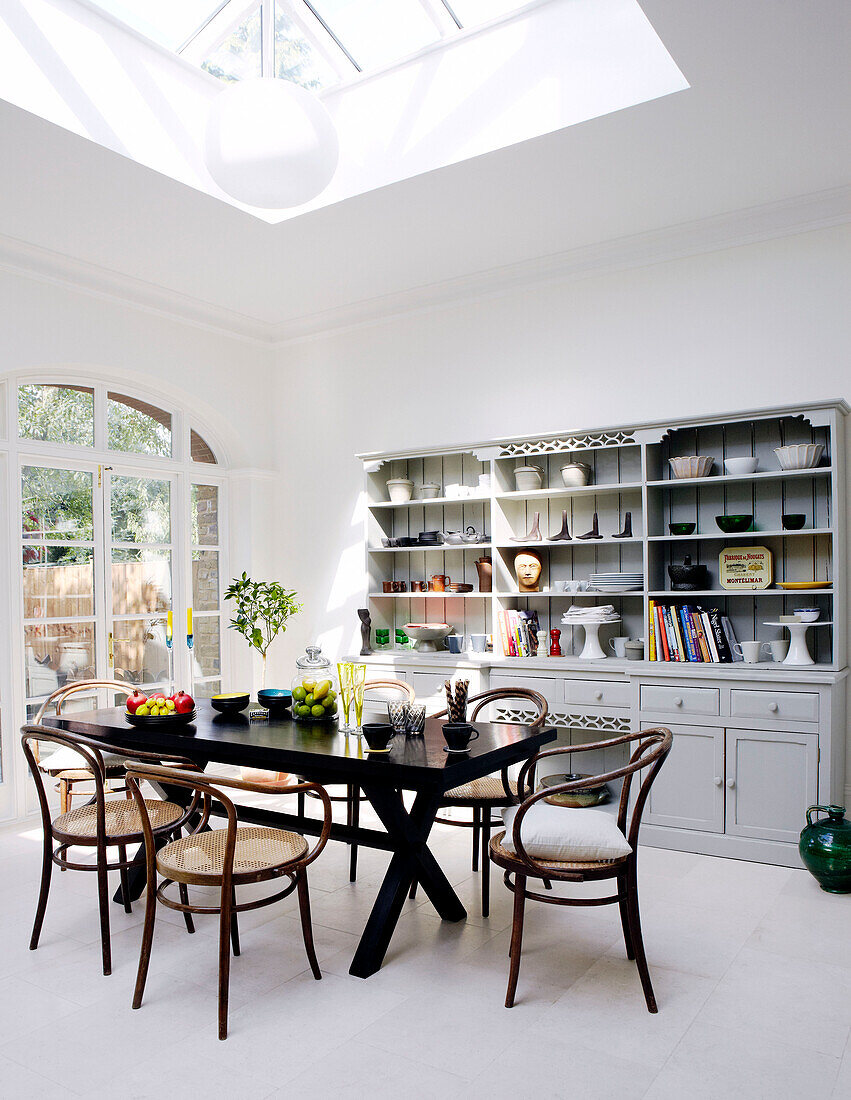 Kitchen dresser with table and chairs under sunlit skylight