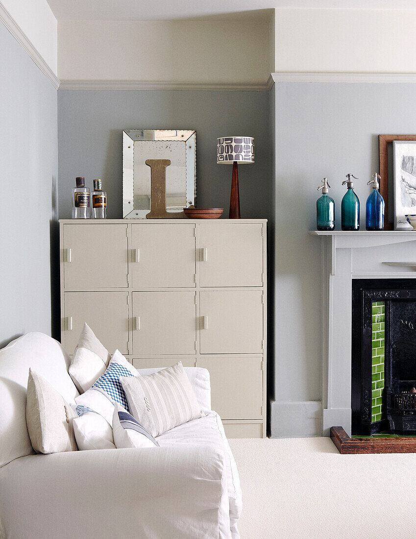 White two seater sofa and storage unit with soda bottles on original fireplace