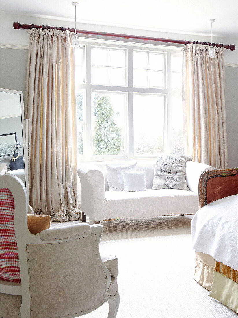 White two seater sofa in sunlit bedroom window