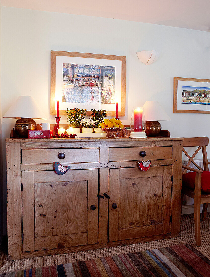 Lit candles on wooden sideboard at Christmas