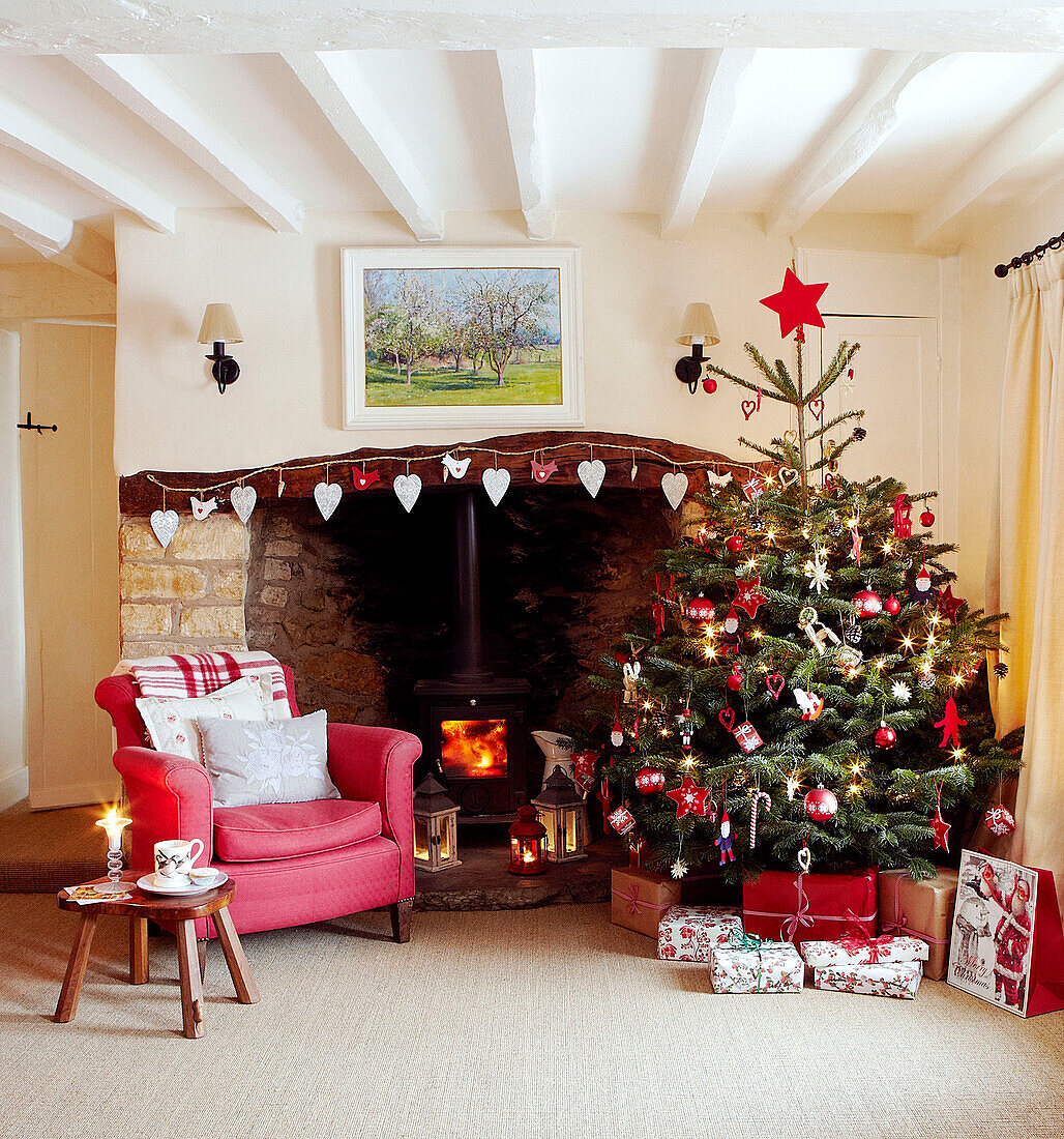 Weihnachtsbaum und roter Sessel am offenen Kamin mit herzförmigen Dekorationen