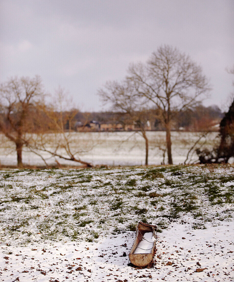 Tiertrog auf winterlichem Feld mit Schneefall
