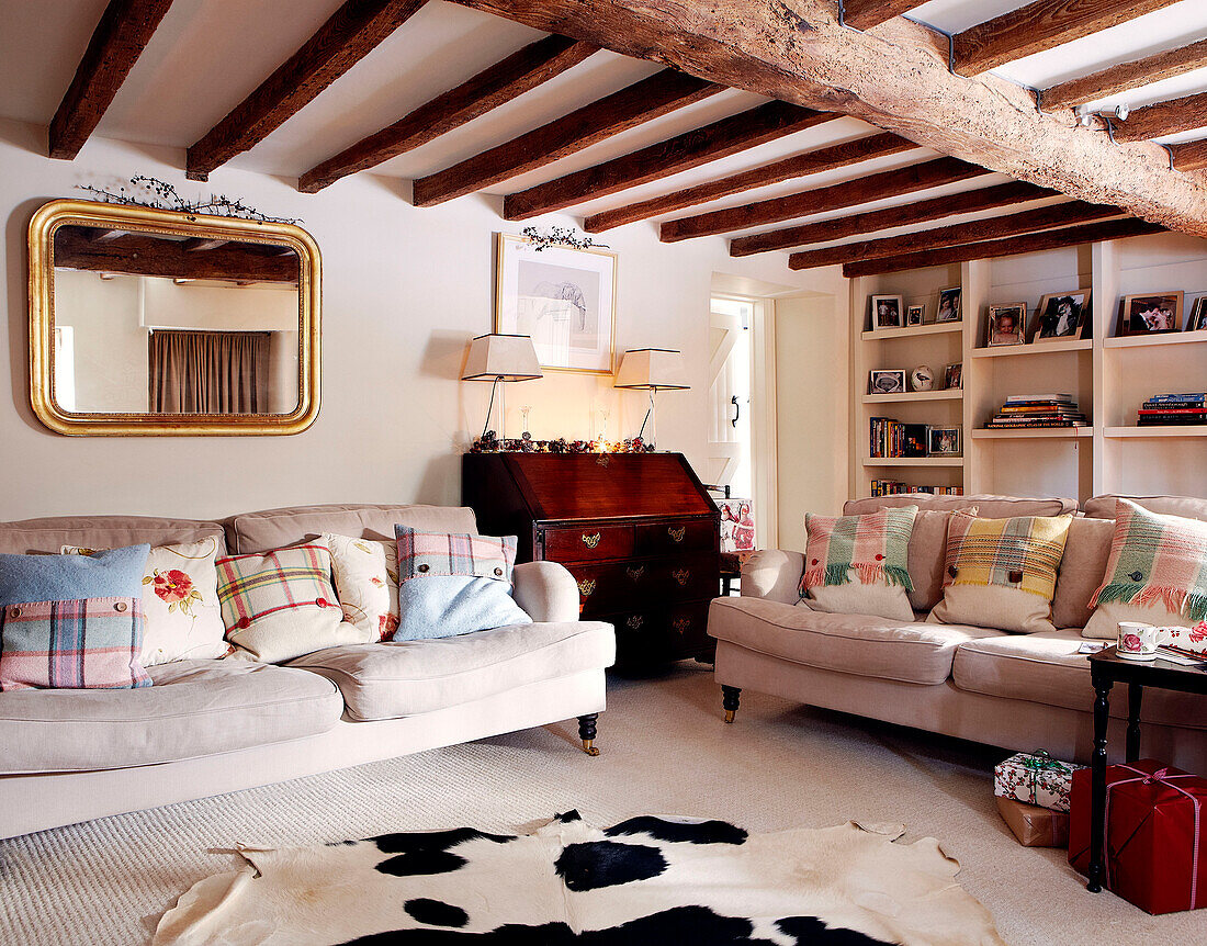 Cremefarbene Sofas und Schreibtisch im Wohnzimmer eines Landhauses mit Balken