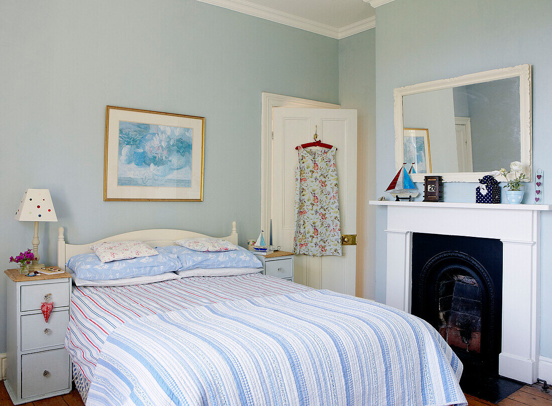 Summer dress hangs on back of door in fresh blue bedroom with original fireplace