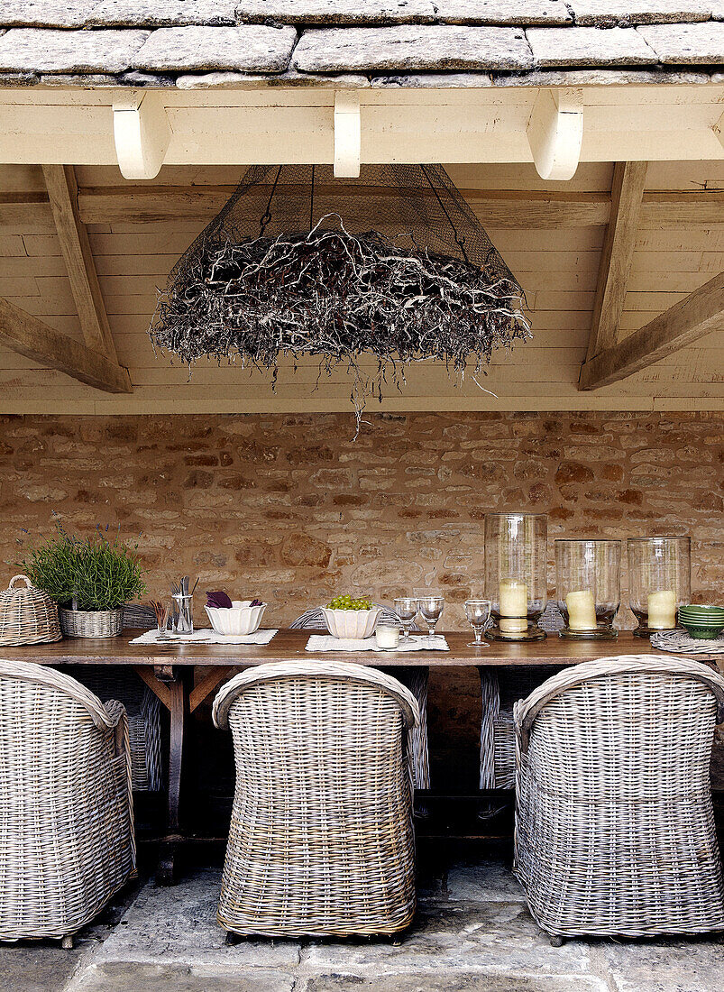 Wicker chairs at table in outdoor room of stone country farm house