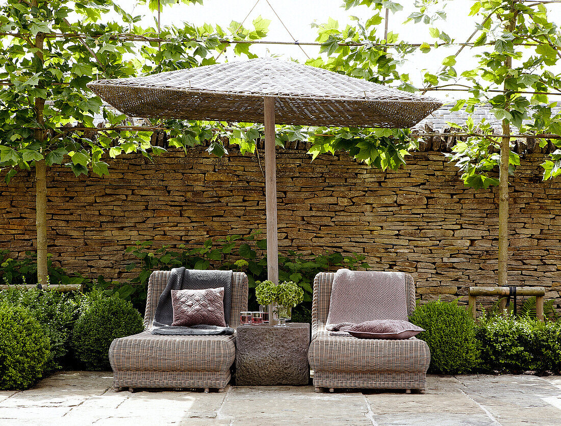 Sun loungers and rattan parasol in farmhouse courtyard exterior