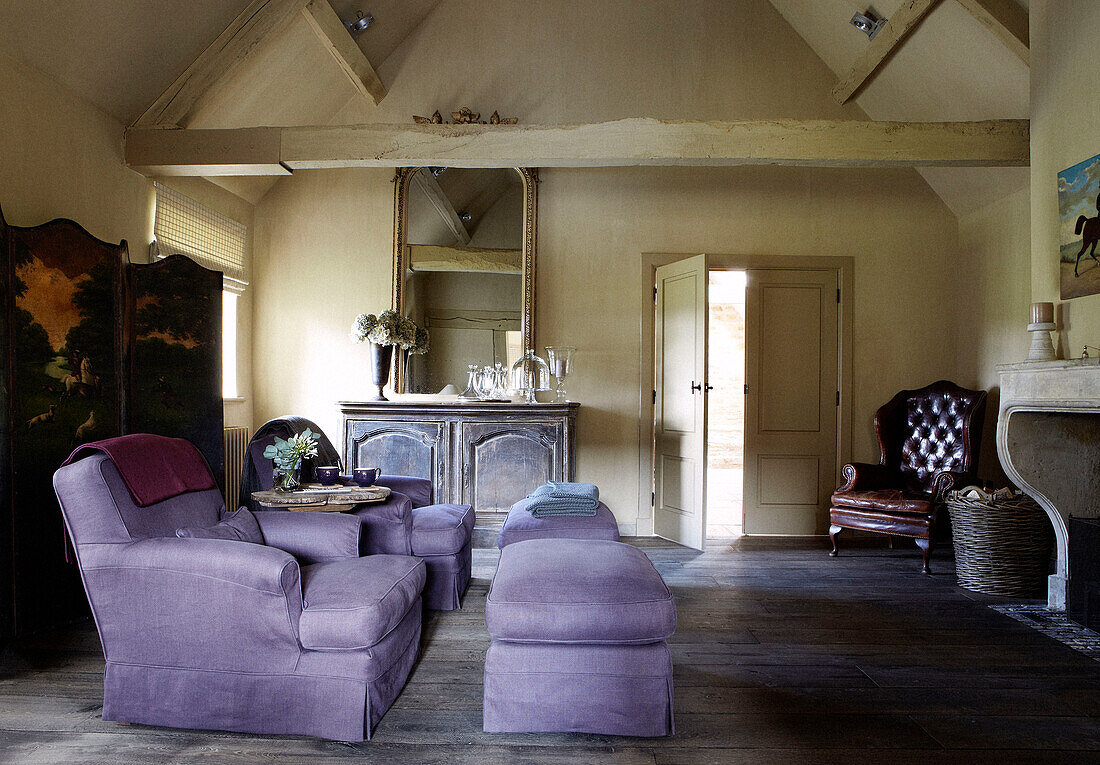 Lilac coloured armchairs with foot rests and folding screen in living room of country home