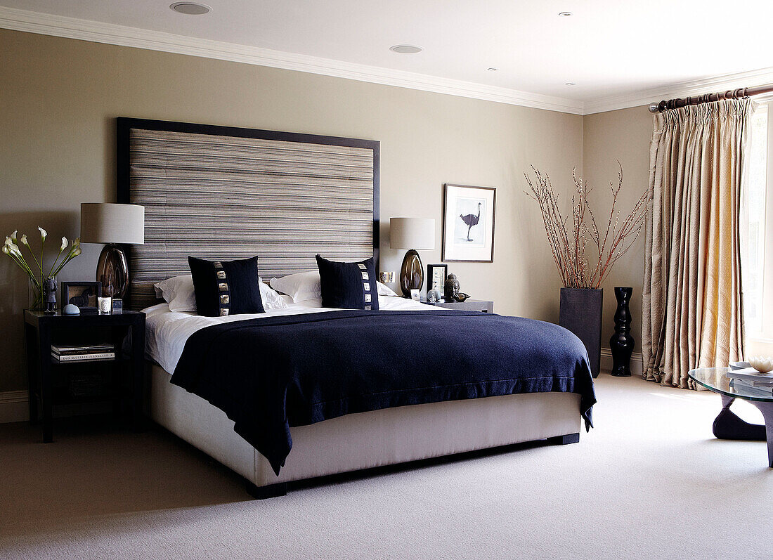 Dark blue covers on bed with side tables and matching lamps