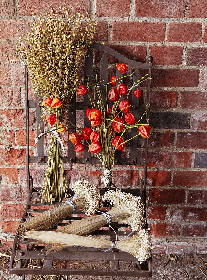 Getrocknete Blumen und Metallstuhl an einer Backsteinmauer in Essex England UK