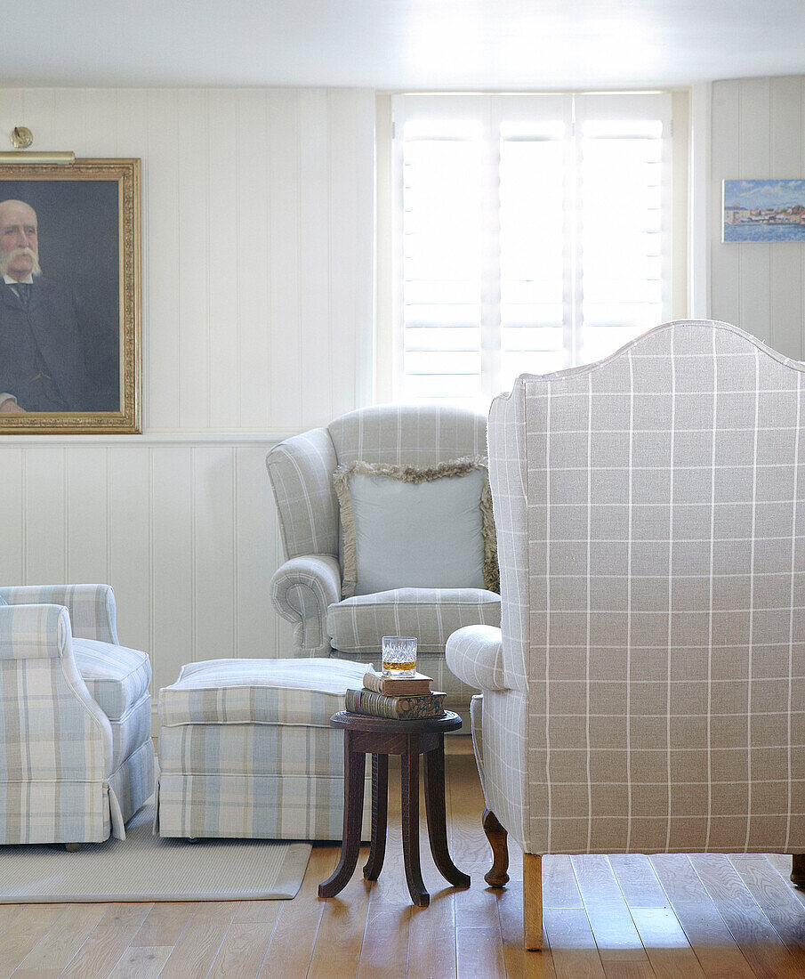 Karierte Sessel und Jalousiefenster im Wohnzimmer eines Hauses in Hampshire, England UK