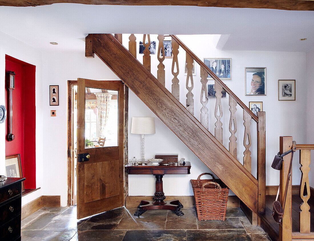 Familienfotos hängen an einer Treppe mit Holzgeländer im Eingangsbereich mit Fliesenbelag