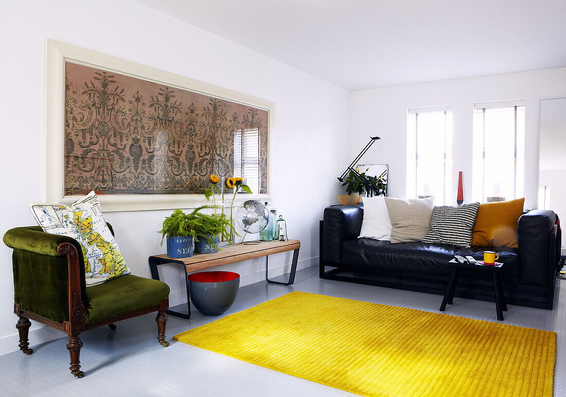 Armchair and side table with black leather sofa in Newcastle living room England UK