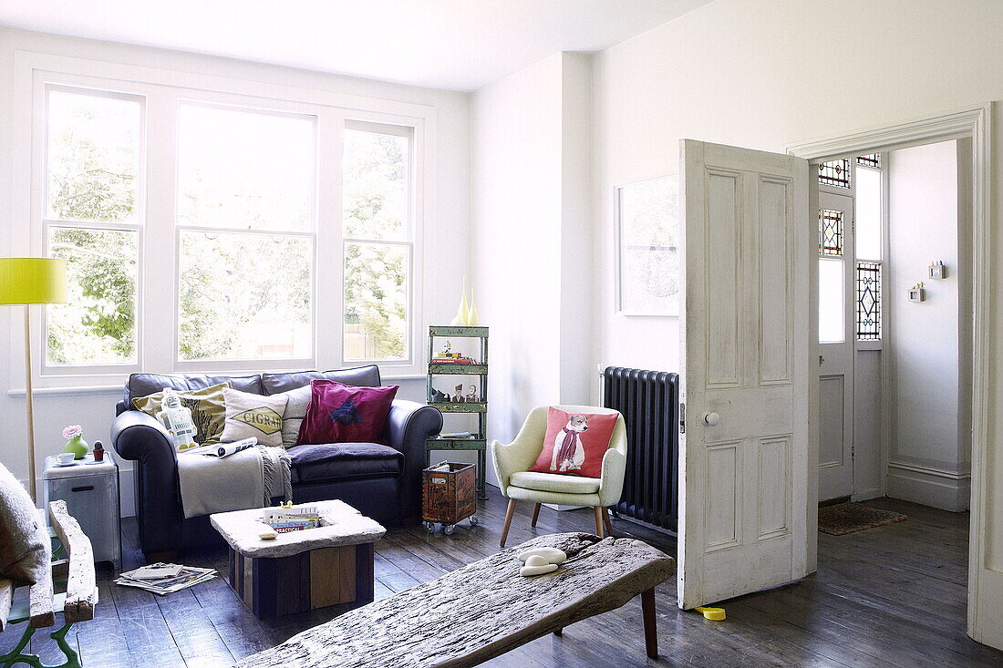 Sofa below uncurtained window with driftwood table in London family home UK