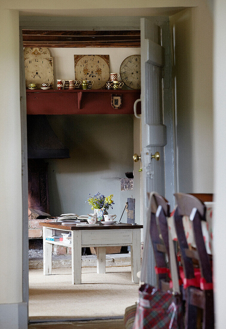 Blick durch die Tür zum Couchtisch im Wohnzimmer eines Bauernhauses in Oxfordshire, England, UK