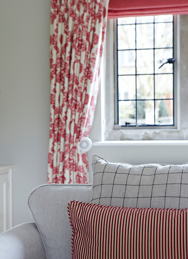 Gestreifte und karierte Kissen auf einem Sofa in einem Wohnzimmer in Oxfordshire mit geblümten Vorhängen, Detail, England, UK