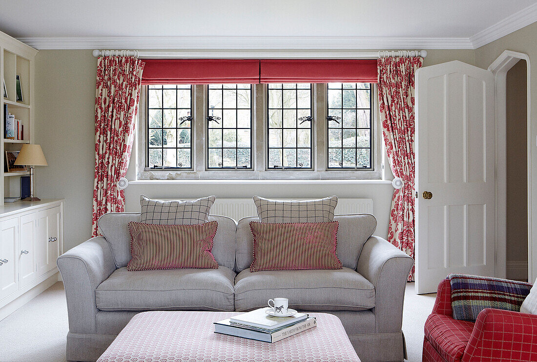 Striped cushions on sofa in Oxfordshire living room with floral curtains, England, UK