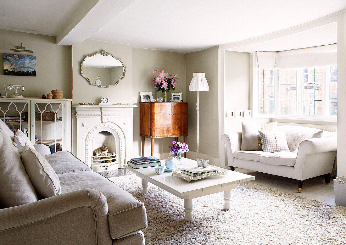 Painted white coffee table with vintage wooden cabinet in living room of Oxfordshire home, England, UK