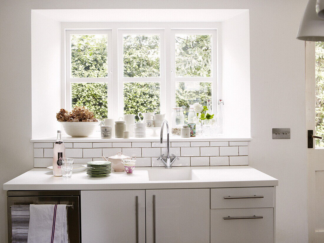 Keramikgeschirr auf sonnenbeschienener Fensterbank mit Spülbecken in modernem Cottage in Oxfordshire, England, UK