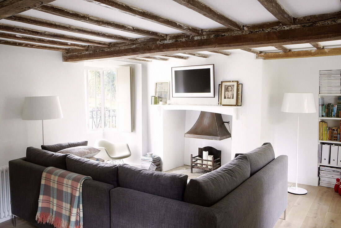 Graues Sofa im Wohnzimmer mit Balken in einem modernen Landhaus in Oxfordshire, England, UK