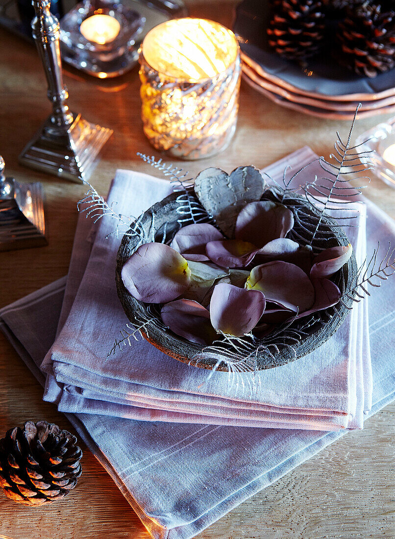 Lit candle and flower petals on dining table in festive Oxfordshire home, England, UK