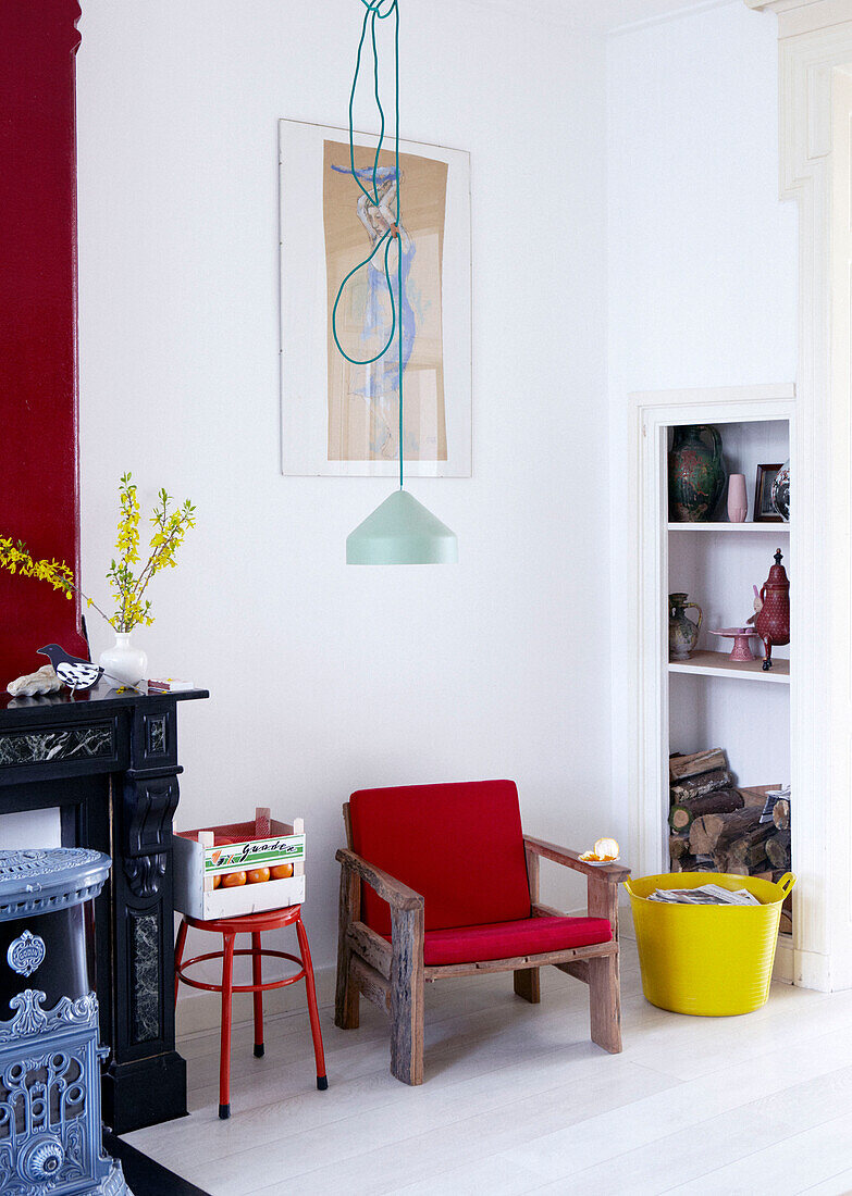 Roter Holzsessel zwischen Regalen und Kamin in einer modernen Wohnung, Amsterdam, Niederlande