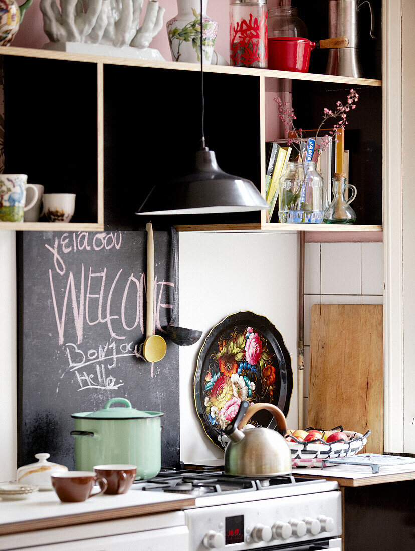 Pan and kettle on hob with blackboard and shelving in kitchen of contemporary apartment, Amsterdam, Netherlands