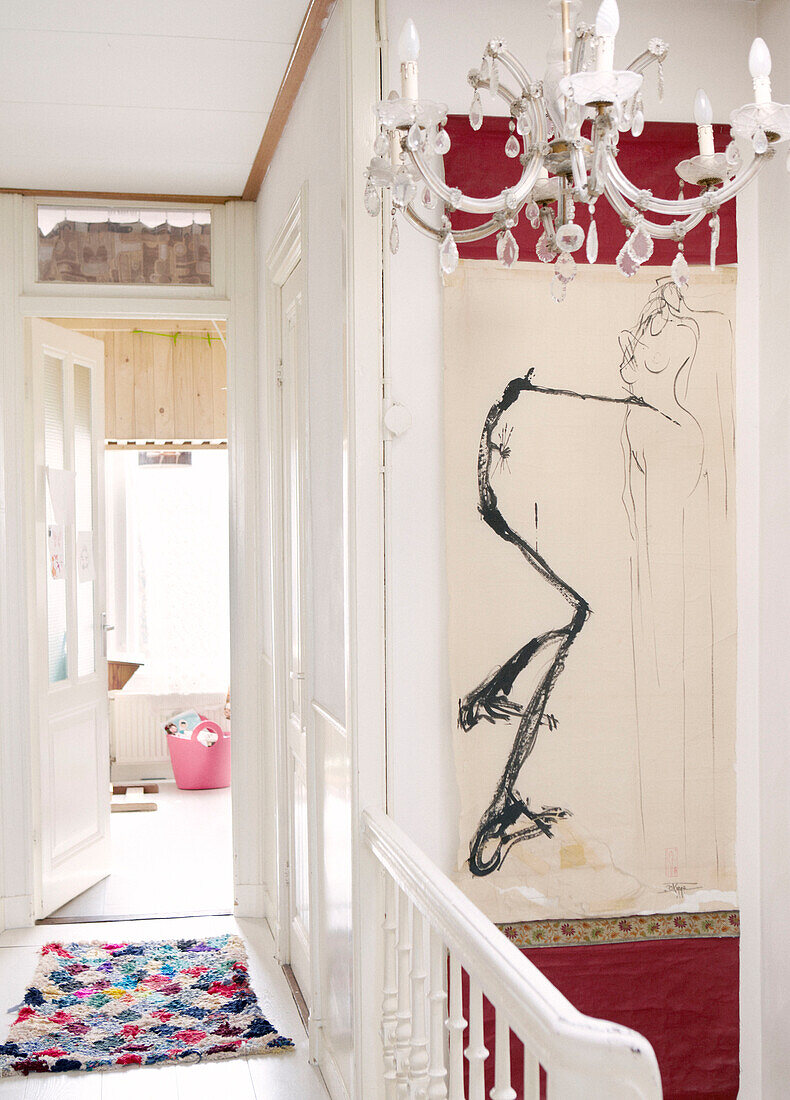 Chandelier and modern art with patterned rug on landing of contemporary apartment, Amsterdam, Netherlands