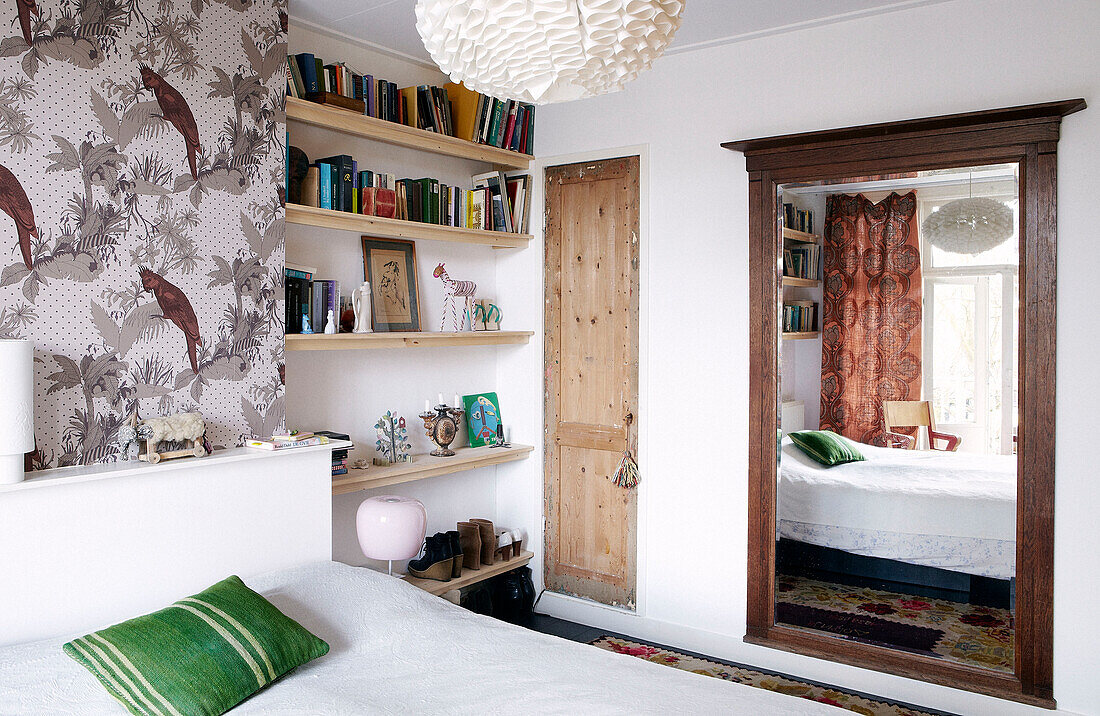 Architectural salvage in contemporary bedroom with bookshelves and patterned wallpaper, Amsterdam, Netherlands