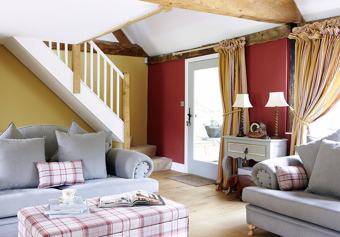 Hellblaue Sofas mit karierten Kissen in einem gelb-roten Wohnzimmer, Oxfordshire, England, UK