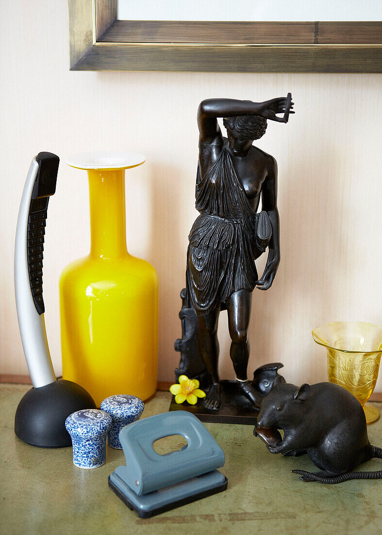 Yellow vase with black figurine and hole punch in London townhouse England UK