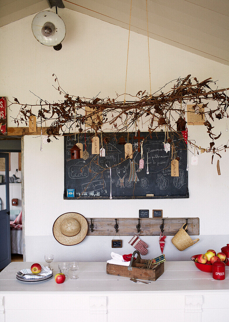 Zweigarrangement über einem Tisch mit Äpfeln in einem umgebauten Schulhaus in der Bretagne, Frankreich