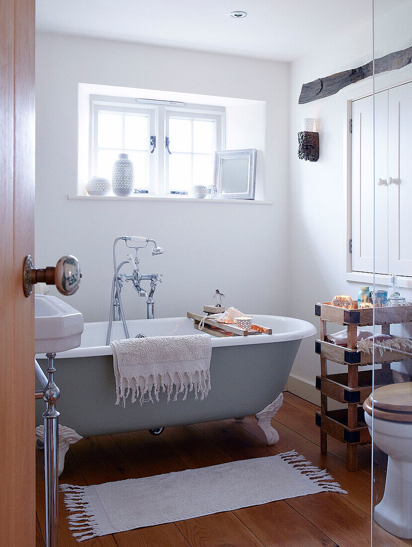 Freistehende rollende Badewanne unter dem Fenster im Badezimmer eines Landhauses in Devonshire UK