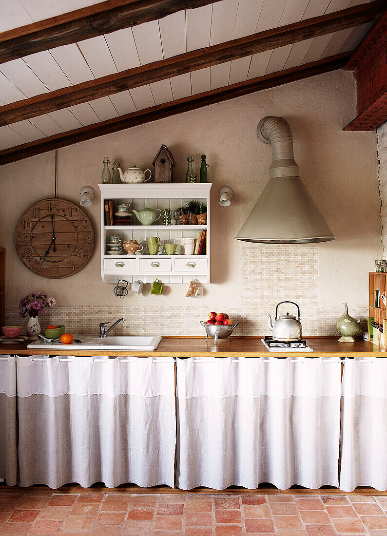 Dunstabzugshaube über einer Küchenarbeitsplatte mit wandmontierten Regalen in einem bretonischen Bauernhaus Frankreich
