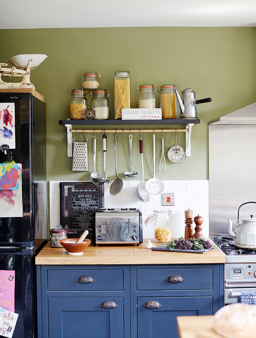 Dried food in storage jars above worktop in blue Kent kitchen England UK