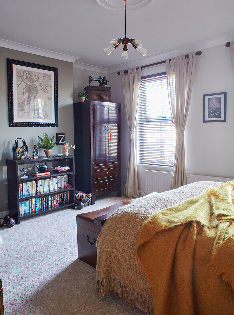 Polierter Kleiderschrank und Bücherregal am Fenster im Schlafzimmer eines Hauses in Kent, England, UK