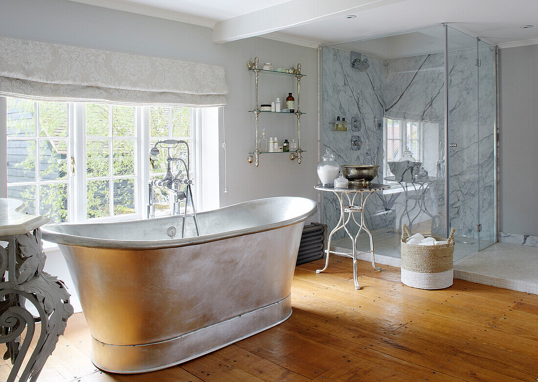 Freistehende Metallbadewanne am Fenster mit Glasduschkabine in einem Haus in Buckinghamshire UK