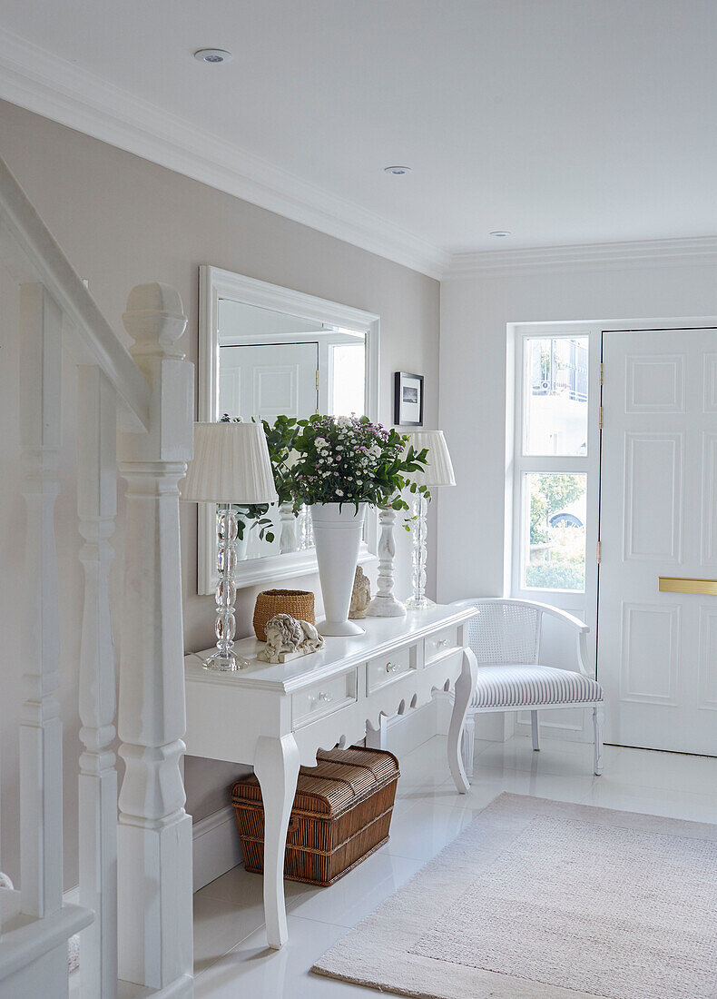 Pair of matching lamps on console with mirror in white entrance hall of York townhouse England UK