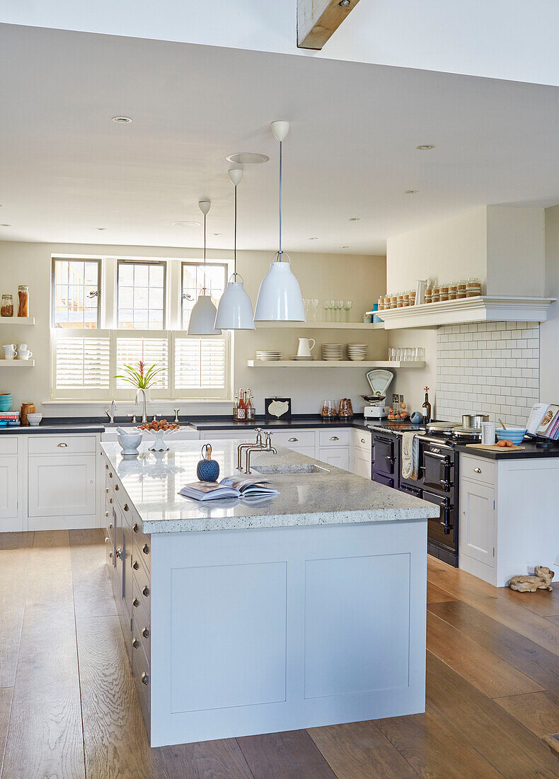 Weiße Pendelleuchten hängen über einer Kücheninsel in einem modernisierten Landhaus in Northumbria UK