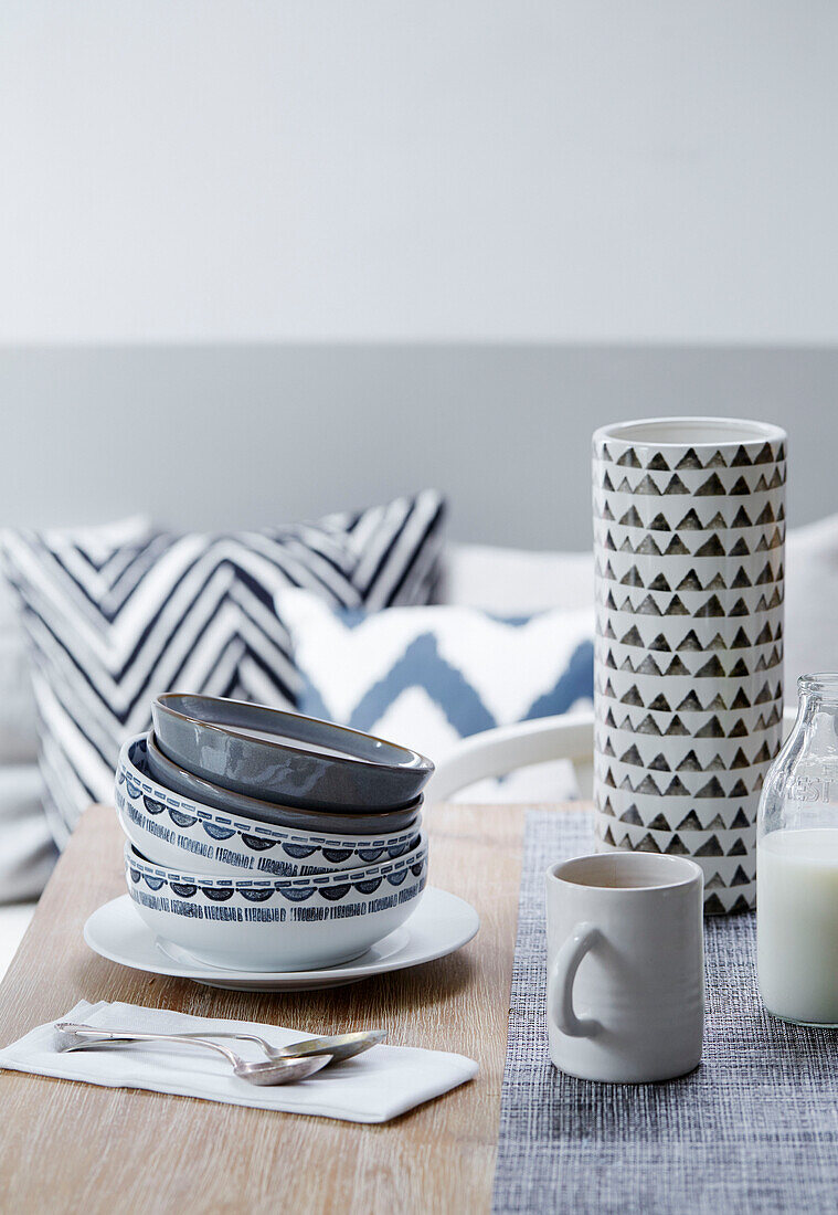 Bowls and vase with mug and spoons on dining table in studio, UK