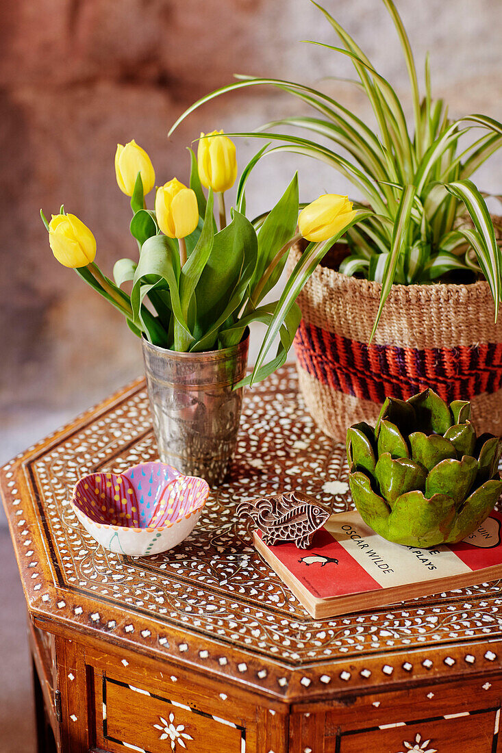 Gelbe Tulpen und Spider-Pflanze mit Ornamenten auf indischem Tisch mit Intarsien in einem Mühlenhaus aus dem 18. Jahrhundert in Northumbria, UK